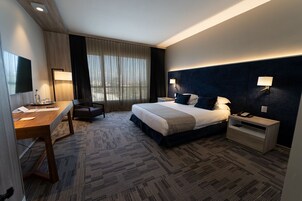 Una habitación de hotel moderna con una cama grande, un escritorio, una silla y un televisor.