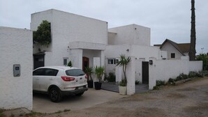 A white building with a car parked in front. - Casa Av. Costanera sn Sector Casino (Coquimbo)