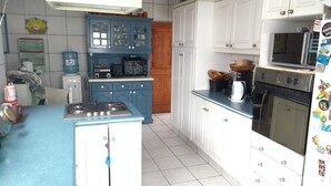 A kitchen with a stove, microwave, and oven. There are cabinets and a water dispenser. - Casa Av. Costanera sn Sector Casino (Coquimbo)