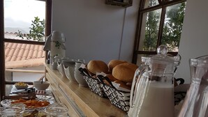A breakfast buffet setup with various food items, beverages, and utensils. - Marco Wasi - San Blas (Cusco)