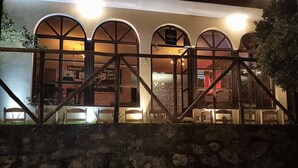 A stone wall with a rustic wooden gate in front of a building with arched windows. - Marco Wasi - San Blas (Cusco)