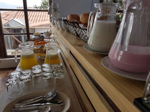 A breakfast buffet with various food items, drinks, and utensils.