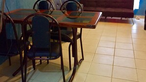 A dining area with a table and chairs, a sofa, a fan, and a window with curtains. - Apartamento PlayaDelCarmen 627 by Sinbad (Playa del Carmen)