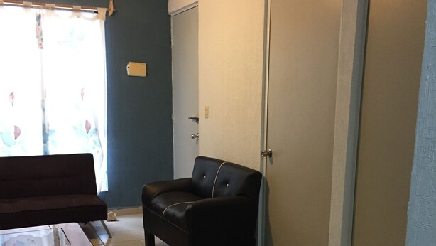 A room with a sofa, a small black chair, a table, and a door. - Apartamento PlayaDelCarmen 627 by Sinbad (Playa del Carmen)