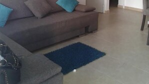Ein Wohnzimmer mit einem braunen Sofa, einem blauen Teppich und einem Blumenbild an der Wand.