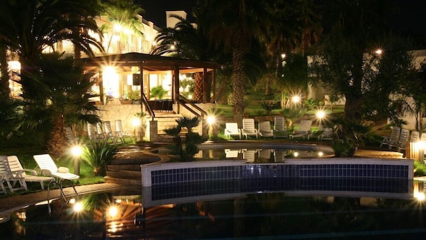 Area piscina notturna con sedie a sdraio, un'area lounge coperta e una fontana alimentata a energia solare.