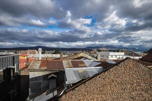Vista de un paisaje urbano con edificios, una cordillera y un cielo nublado.