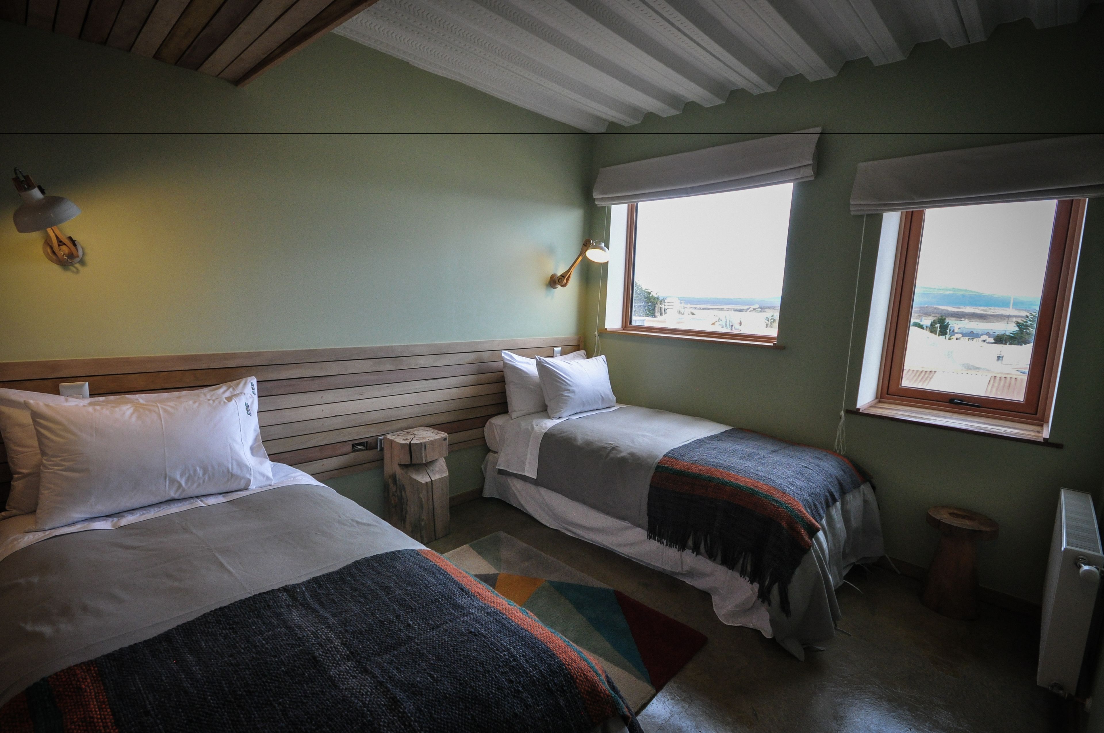 Una habitación con dos camas, cabecero de madera, una mesita pequeña y un radiador.