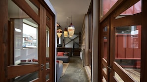 Un couloir avec des portes en bois, un escalier et des lampes suspendues.