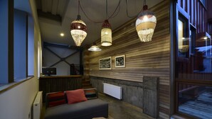 Une pièce chaleureuse avec un canapé, un mur en bois et des lampes suspendues.