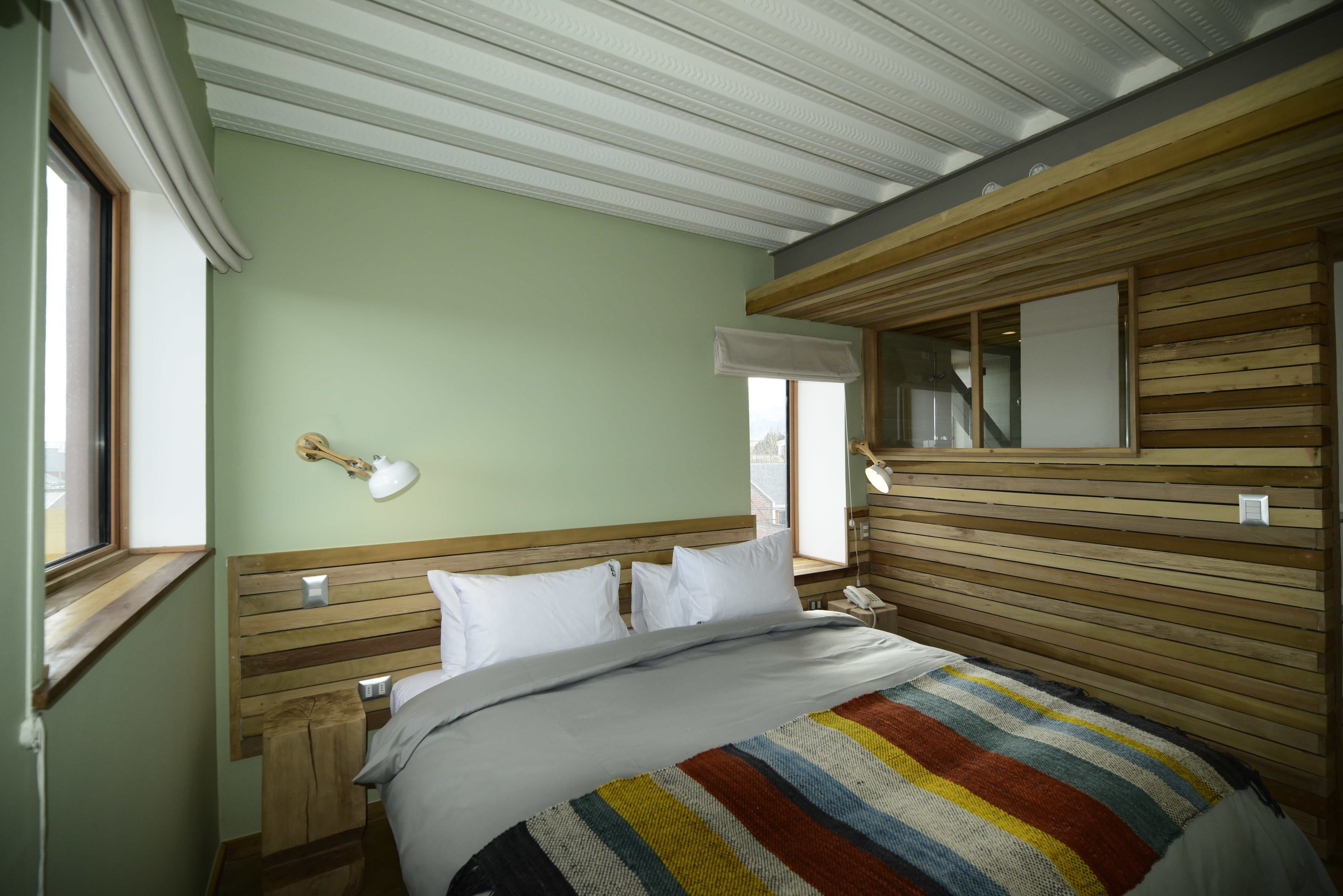 Ein Schlafzimmer mit einem Holz-Kopfteil, einer gestreiften Bettdecke und einem Nachttisch mit einer Lampe.