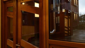 Une façade en bois avec de grandes fenêtres et une porte en verre.