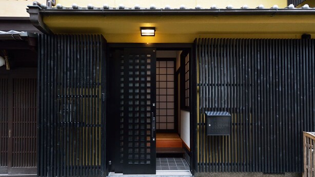 A traditional Japanese entrance with a sliding gate, a small porch, and a mailbox. - karaku Inn (Kyoto)