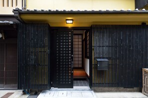 A traditional Japanese entrance with a sliding gate, a small porch, and a mailbox. - karaku Inn (Kyoto)
