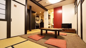 A traditional Japanese room with tatami mats, a low table, and a television. - karaku Inn (Kyoto)