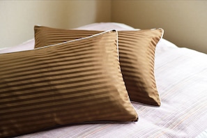 Two pillows with a striped pattern on a bed with a striped bedspread. - karaku Inn (Kyoto)