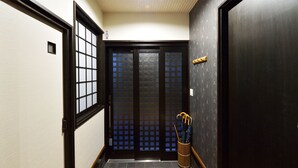 A hallway with a sliding door, a small window, and a wooden floor. - karaku Inn (Kyoto)