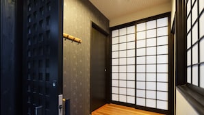 A traditional Japanese room with tatami flooring, shoji screens, and a sliding door. - karaku Inn (Kyoto)