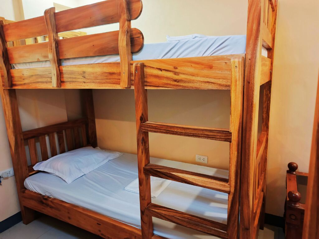 A bunk bed with a wooden frame and white bedding.