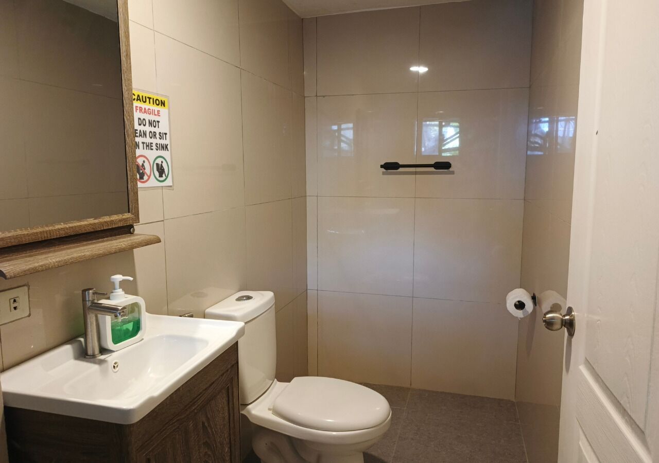 Et badeværelse med toilet, håndvask og en advarselsskilte.