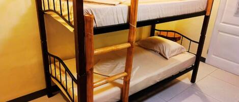A bunk bed with a wooden frame and metal railings, a white mattress, and a single pillow.