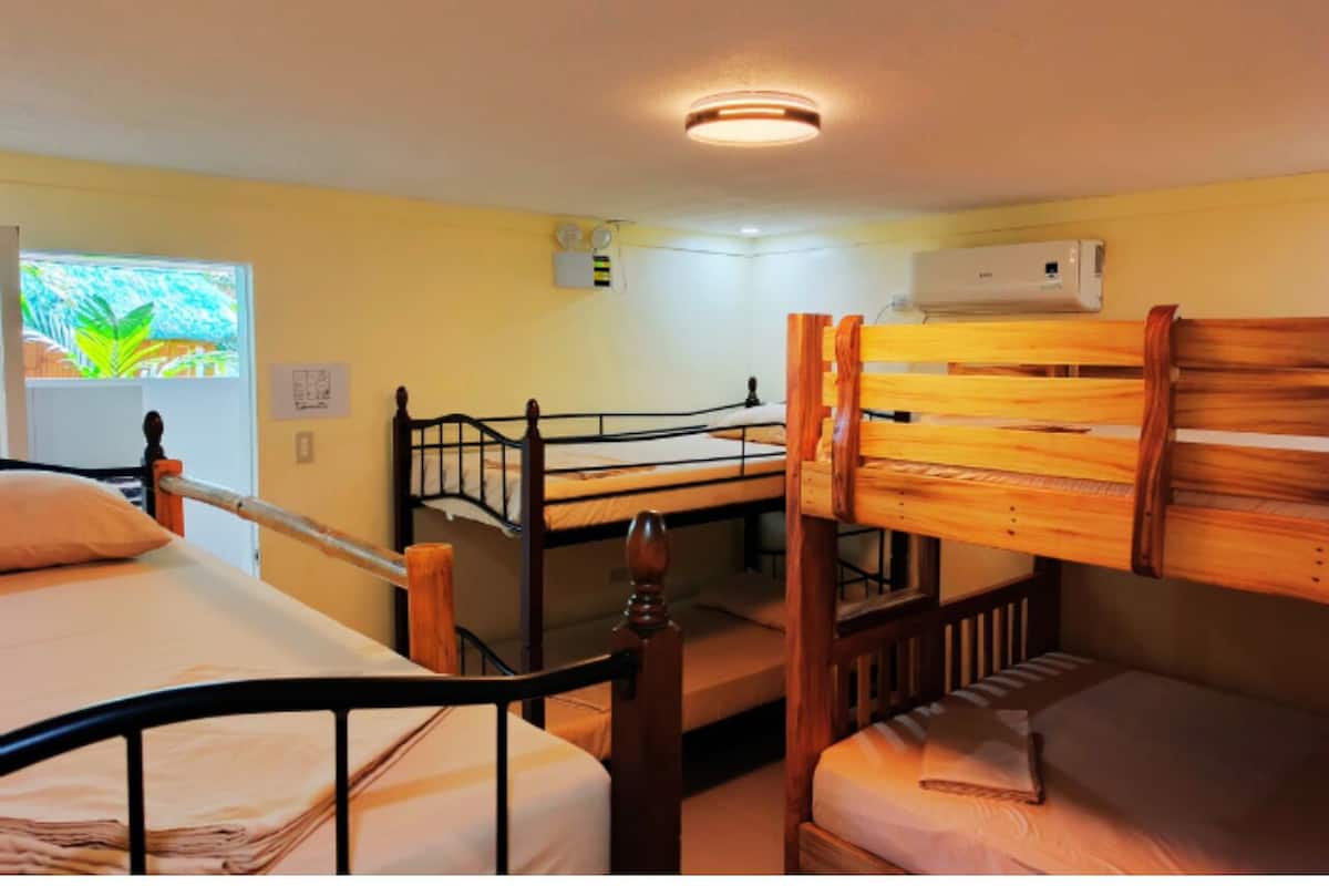 Un dormitorio con literas, una ventana con vistas, un equipo de aire acondicionado y una luz en el techo.