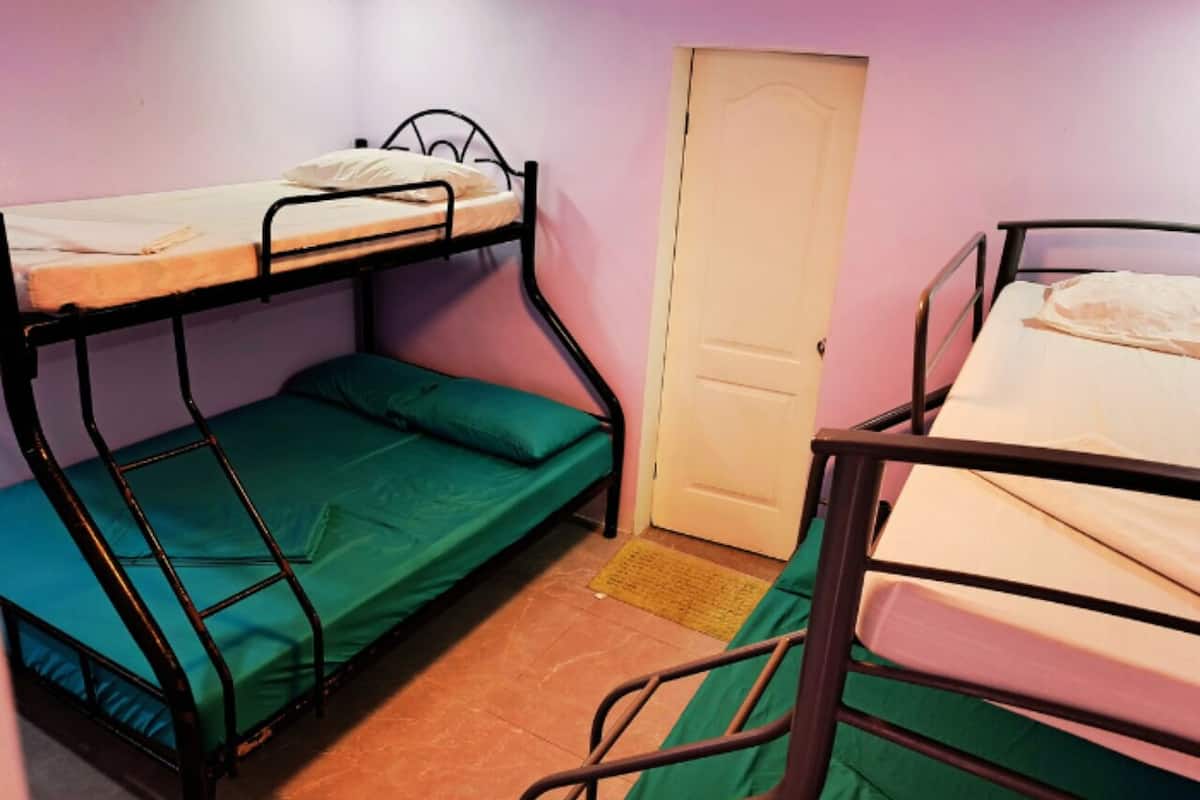 Un dormitorio con literas, una puerta y piso de baldosas.