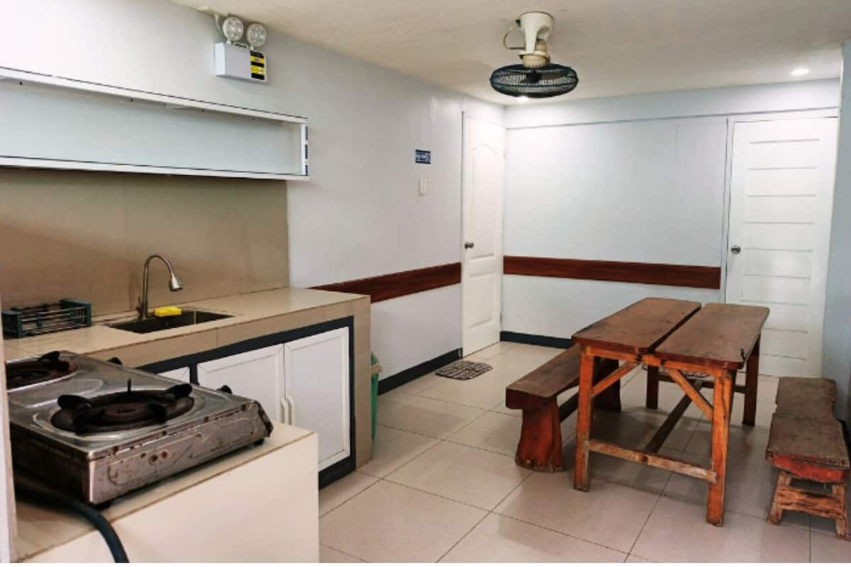 Una cocina compacta con estufa a gas, un lavamanos, una mesa de madera y un banco.