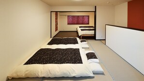 A room with two beds, a window with red blinds, a ceiling light, and a tatami mat floor. - Raku Inn (Kyoto)