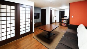 A modern living room with a wooden floor, a sofa, a coffee table, and sliding doors with a grid pattern. - Raku Inn (Kyoto)