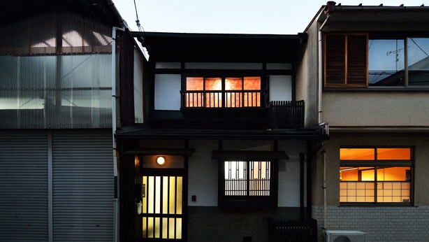 A traditional Japanese house with a sliding door, a small porch, and a window with a view of the city at night. - Raku Inn (Kyoto)