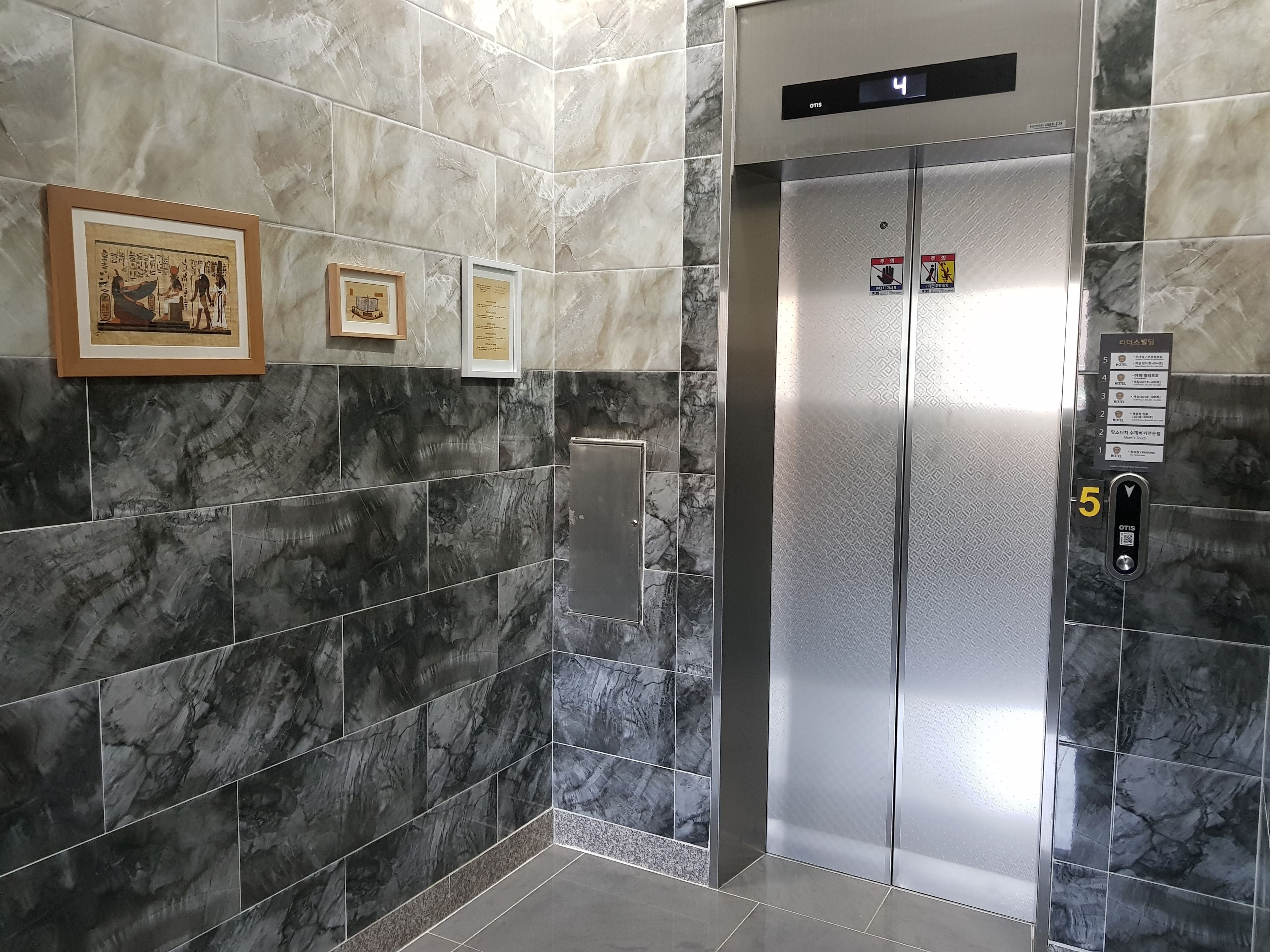 An elevator with marble walls and numbered floor indicators.