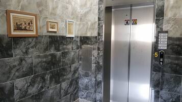 An elevator with marble walls and numbered floor indicators.