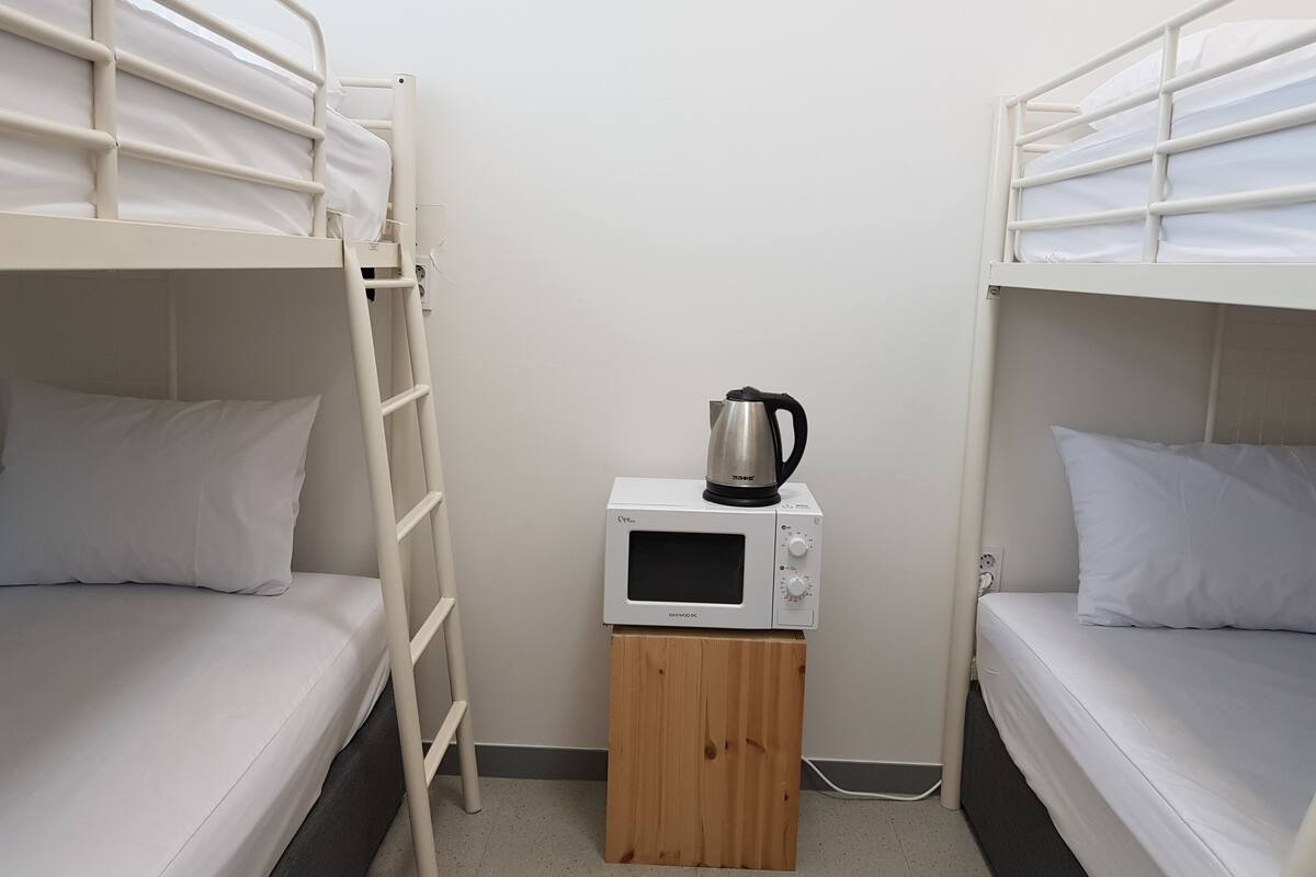 Un dormitorio con dos literas, un armario de madera y un microondas.