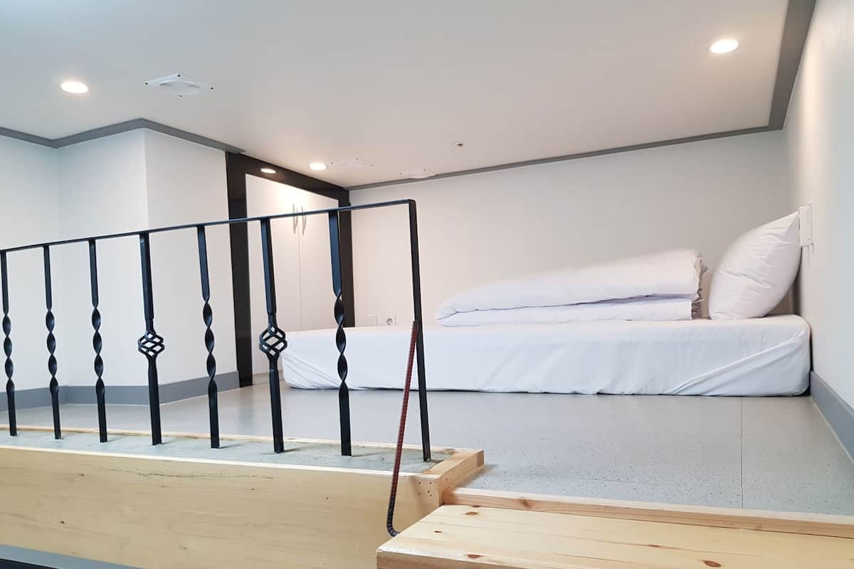 Un dormitorio moderno con cama, un banco de madera y una barandilla.