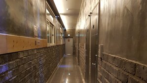 Een gang met aan de ene kant een bakstenen muur en aan de andere kant een houten balie, en een rij lockers.