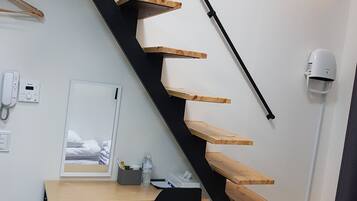 A modern room with a black staircase, wooden desk, and a black chair.