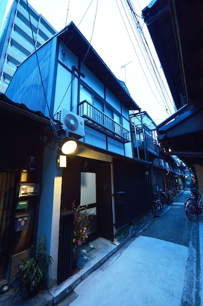 A narrow urban street with buildings, a visible ATM, and a bicycle parked on the sidewalk.
