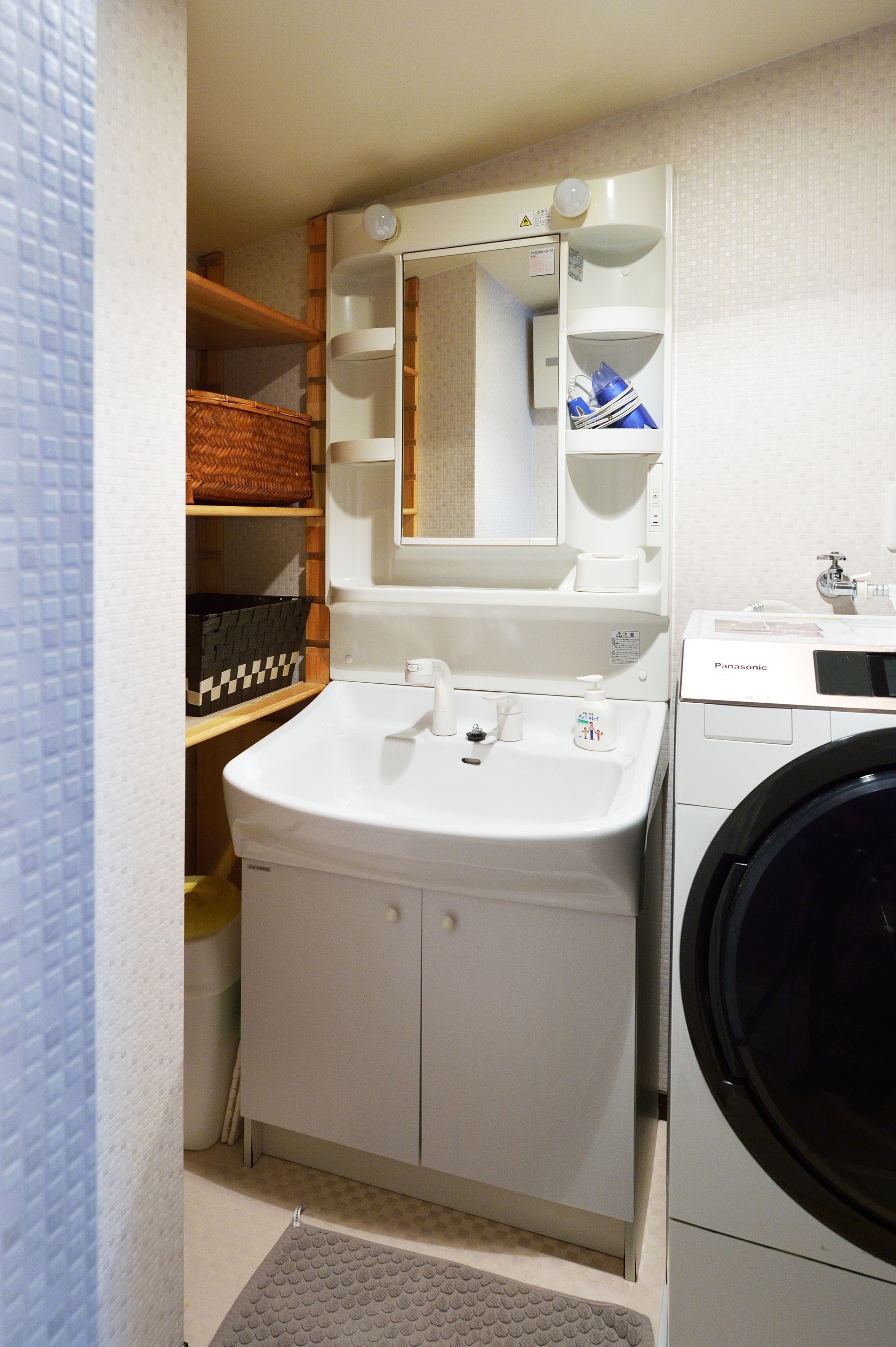 A compact bathroom with a sink, mirror, and washing machine.