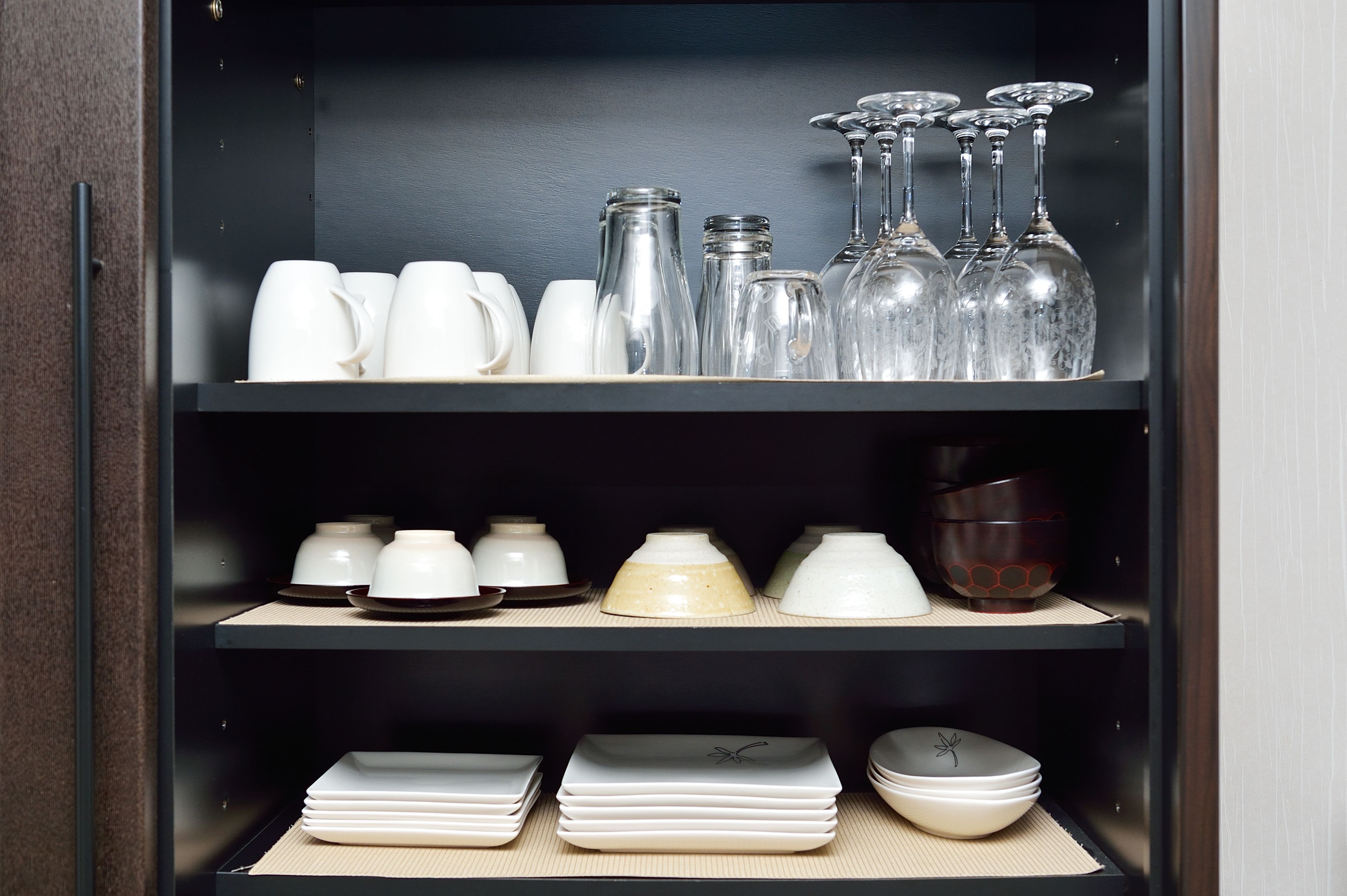 Un meuble de cuisine contenant divers articles en verre, de la vaisselle en céramique et des assiettes.
