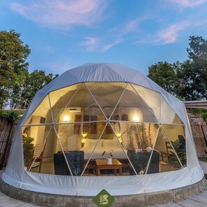 A dome-shaped tent with a glass front, interior lighting, and a seating area with a table and chairs. - Bansaeo Garden and Resort (Chiang Saen)