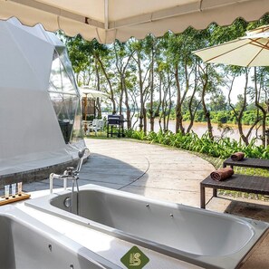 A spa area with a large bathtub, a grill, and outdoor seating. - Bansaeo Garden and Resort (Chiang Saen)
