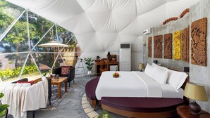 A spacious tented room with a bed, a desk, and a view of greenery outside. - Bansaeo Garden and Resort (Chiang Saen)