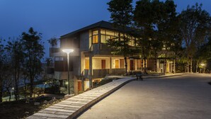 A modern building with a curved driveway, large windows, and a well-lit entrance area. - Bansaeo Garden and Resort (Chiang Saen)