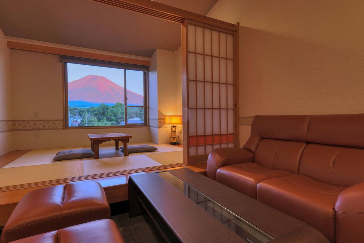 Une pièce de style japonais traditionnel, avec un sol recouvert de tatamis, une table basse, un banc rembourré et une vue sur une montagne.