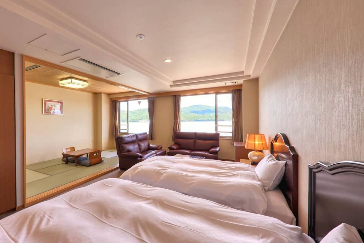 Une chambre d’hôtel avec deux lits, un bureau et une vue sur l’extérieur.