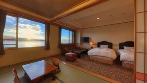 A hotel room with a large window, a sofa, a bed, a table, and a TV. - Fujimatsuzono Hotel (Yamanakako)
