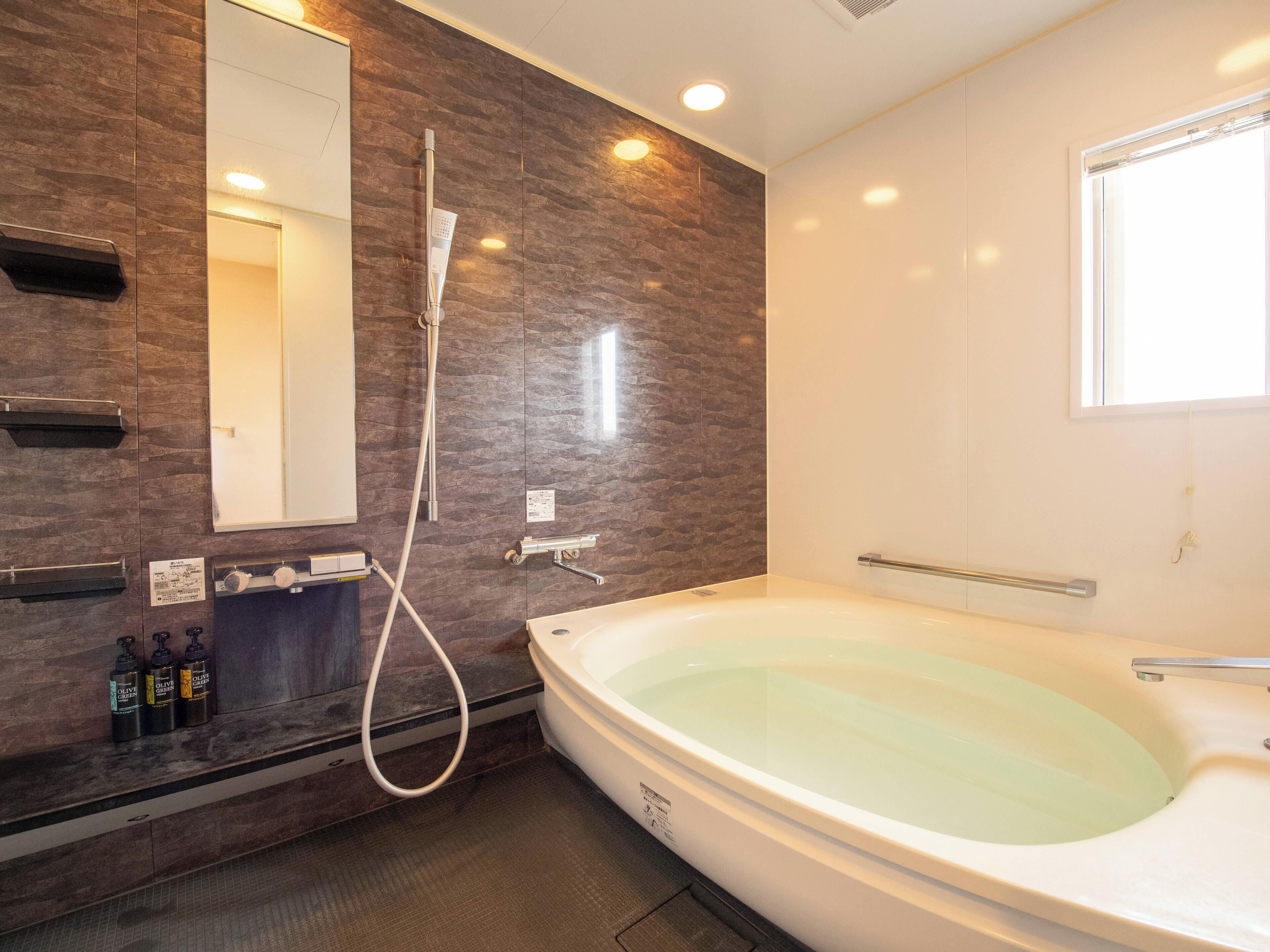 A modern bathroom with a large bathtub, a shower, and a vanity with toiletries.