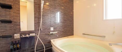 A modern bathroom with a large bathtub, a shower, and a vanity with toiletries.