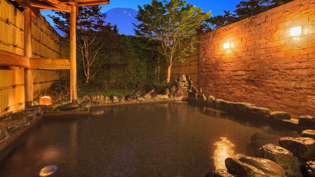 A hot spring bath area with wooden structures and stone walls. - Fujimatsuzono Hotel (Yamanakako)